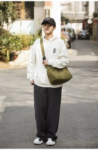 Detail of army green nylon crossbody bag paired with streetwear hoodie and sneakers