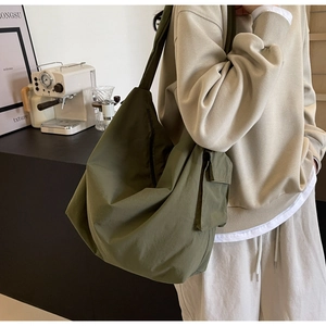 Detail of army green nylon crossbody bag showing the side pocket and large storage capacity