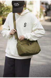 Detail of army green nylon messenger bag with double front zippers and wide shoulder strap