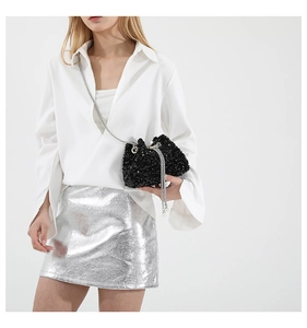 Detail of black sequin bucket bag with silver chain strap and elegant pearl charm accents