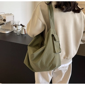 Detail view of the olive green canvas crossbody bag featuring a wide strap and side flap pocket