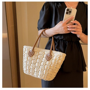Close-up of woven tote bag with premium cream mesh texture and brown leather handles