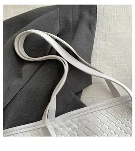 Détail d'un sac à main blanc en similicuir tressé avec coutures et doubles anses