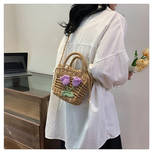 Detail of hand-woven straw crossbody bag with purple crochet tulip floral accents