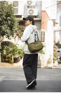Olive green nylon crossbody bag shown in a stylish street setting for daily commute
