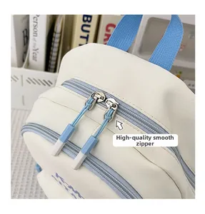 Detail of high-quality smooth double zippers with stylish light blue pull tabs on a white backpack