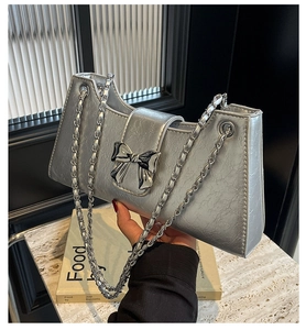 Dettaglio della pelle argentata pieghettata con un fiocco metallico su una borsa alla moda