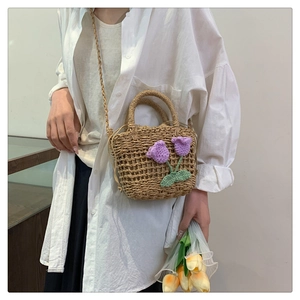 Detailed close-up of woven straw bag with purple crochet tulips and drawstring closure