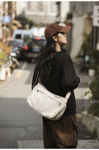Street style shot of model wearing a beige nylon crossbody messenger bag with wide strap