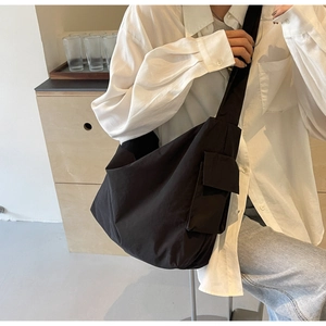 Detail of a black minimalist nylon messenger bag with wide shoulder strap and side pocket