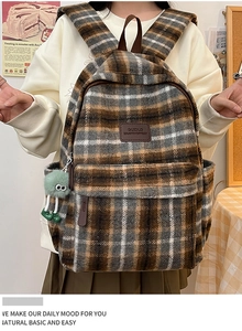 Détail d'un sac à dos à carreaux rétro marron avec un porte-clé monstre en peluche