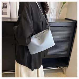 Detail of light blue nylon shoulder bag with adjustable strap shown on female model