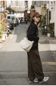 Outdoor street style view showing the beige nylon crossbody bag paired with casual outfit
