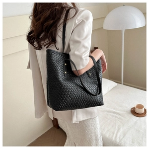 Détail d'un grand sac cabas noir tressé avec texture cuir de qualité et rivets métalliques