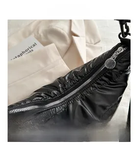 Detail of silver metal zipper and quilted texture on black shiny nylon shoulder bag