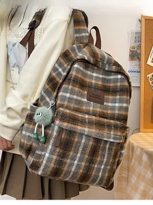 Détail d'un sac à dos à carreaux marron avec texture pelucheuse et un charm vert