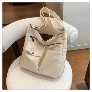 Borsa a tracolla alla moda in nylon crema con design multitasche su poltrona in pile
