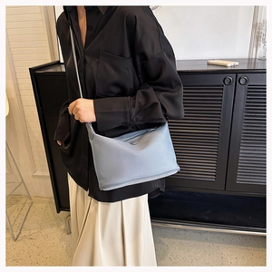 Detail of light blue minimalist crossbody bag showing smooth matte texture and top zipper