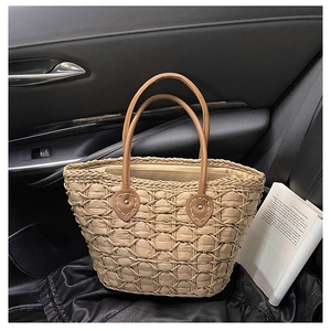 Chic woven straw tote bag with brown leather handles placed on a car seat with a book