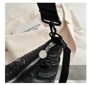 Detail shot of smooth silver metal zipper on black quilted down-filled crossbody bag