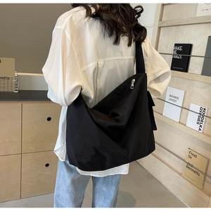 Rear view of model wearing black nylon crossbody bag in a cozy modern bookstore