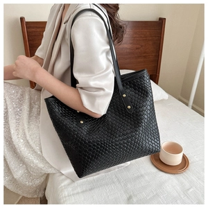 Détail d'un grand sac cabas noir en cuir synthétique tressé avec fines lanières