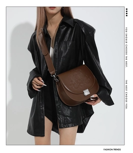 Détail du sac de selle marron avec motif d'étoile embossé et fermoir métallique