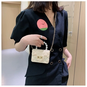 Détail d'un mini sac matelassé avec poignée en perles et chaîne dorée sur le mannequin
