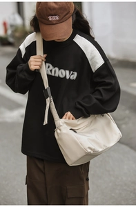 Outdoor street style shot of the cream nylon crossbody bag with adjustable strap details
