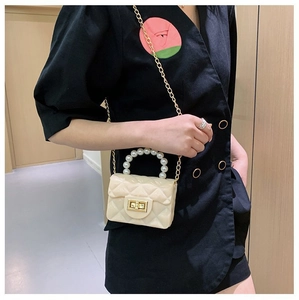 Détail d'un mini sac gelée crème avec poignée perles, chaîne dorée et matelassage