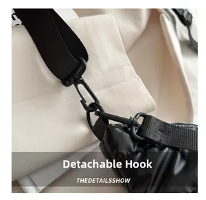 Detailed close-up of a black metal detachable hook and nylon strap on a quilted bag