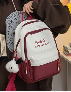 Detail of trendy college style backpack featuring embroidered logo and plush puppy charm