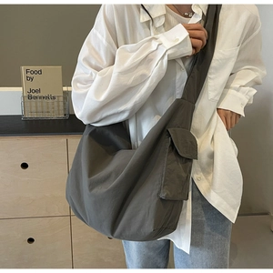 Detailed shot of large dark grey nylon crossbody bag with functional side cargo pocket