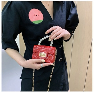 Détail du sac jelly rouge matelassé avec poignée en perles et chaîne dorée