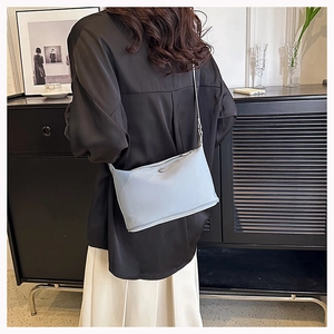Detail view of light blue minimalist crossbody bag styled with a modern outfit