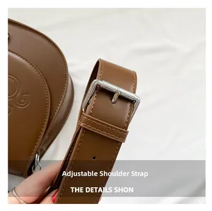 Détail de la bandoulière réglable sur un sac en cuir PU marron avec boucle argentée