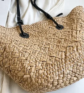Détail d'un sac cabas en paille tissé main avec lanières en cuir noir et texture