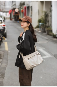 Detail view of the cream nylon crossbody bag featuring practical multi-pocket design for women