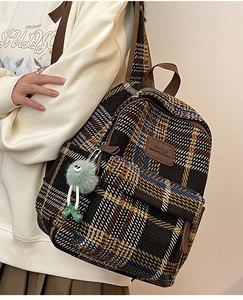 Gros plan du sac à dos à carreaux style britannique avec peluche et étiquette en cuir