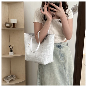 Détail du sac cabas blanc en cuir tressé avec rivets dorés et poignée fine exposée