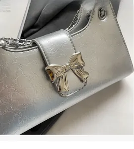 Dettaglio borsa a tracolla in pelle PU argento con chiusura a fiocco e catena metallica