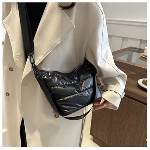 Close-up of a black quilted puffer crossbody bag styled with a cream wool coat for women