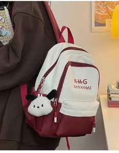 Detailed shot of two-tone burgundy and white polyester backpack with plush charm detail