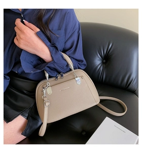 Détails de la texture du cuir grainé beige et des ferrures argentées du sac à main