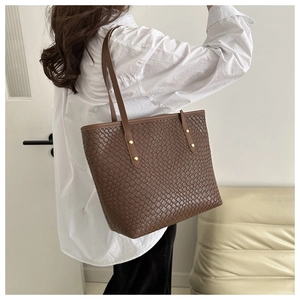 Vue détaillée du sac cabas tressé marron avec texture en cuir et finitions de rivets dorés