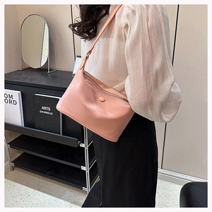 Model wearing a stylish pink leather shoulder bag with zipper and round buckle detail