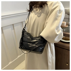 Detailed view of a black quilted down shoulder bag featuring glossy nylon fabric
