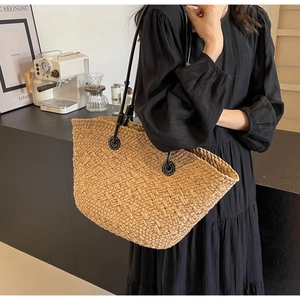 Détail du sac cabas en paille tressée avec lanières en cuir noir et œillets argentés