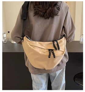 Casual khaki crescent crossbody bag worn by a model in a cozy indoor cafe setting