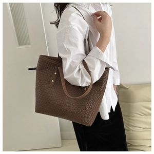 Gros plan d'un sac cabas marron foncé avec texture tissée et rivets dorés